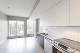 Located at 9922 111 Street in Edmonton's vibrant Oliver neighbourhood, this thoughtfully designed one-bedroom, one-bathroom unit offers a clean, modern aesthetic across a single floor. The open-concept layout maximizes the available space, with light hardwood-style flooring flowing seamlessly throughout the main living areas.

The kitchen is a standout feature, outfitted with a full suite of stainless steel appliances including a French door refrigerator, electric range, built-in microwave, and dishwasher. Flat-panel white upper cabinetry pairs with dark lower cabinets and a crisp white countertop, creating a contemporary two-tone design. A tile backsplash and a stainless undermount sink complete the functional and stylish workspace.

The spacious primary bedroom offers ample room, neutral warm-toned walls, and a sliding double-door closet, providing practical storage in a clean, minimalist setting.

The bathroom is elegantly finished with marble-look tile flooring and surround, a floating dark wood vanity with a white quartz countertop, a backlit mirror, and a soaker tub-shower combination.

A private balcony with glass-panel railings extends the living space outdoors, offering expansive views of the Edmonton skyline, surrounding greenery, and the urban streetscape below — a compelling feature of this well-appointed urban residence.