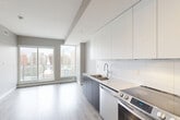 Located at 9922 111 Street in Edmonton's vibrant Oliver neighbourhood, this thoughtfully designed one-bedroom, one-bathroom unit offers a clean, modern aesthetic across a single floor. The open-concept layout maximizes the available space, with light hardwood-style flooring flowing seamlessly throughout the main living areas.

The kitchen is a standout feature, outfitted with a full suite of stainless steel appliances including a French door refrigerator, electric range, built-in microwave, and dishwasher. Flat-panel white upper cabinetry pairs with dark lower cabinets and a crisp white countertop, creating a contemporary two-tone design. A tile backsplash and a stainless undermount sink complete the functional and stylish workspace.

The spacious primary bedroom offers ample room, neutral warm-toned walls, and a sliding double-door closet, providing practical storage in a clean, minimalist setting.

The bathroom is elegantly finished with marble-look tile flooring and surround, a floating dark wood vanity with a white quartz countertop, a backlit mirror, and a soaker tub-shower combination.

A private balcony with glass-panel railings extends the living space outdoors, offering expansive views of the Edmonton skyline, surrounding greenery, and the urban streetscape below — a compelling feature of this well-appointed urban residence.