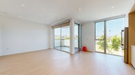This modern residence offers a thoughtfully designed single-floor layout encompassing two bedrooms and two bathrooms. The open-plan living and kitchen area is anchored by large floor-to-ceiling sliding glass doors that lead to a private balcony, flooding the space with abundant natural light and offering panoramic views of palm-lined surroundings. Light wood flooring runs throughout, complementing the clean white walls and recessed lighting that reinforce the home's contemporary aesthetic.

The kitchen is outfitted with flat-front light wood cabinetry extending to the ceiling, white quartz countertops, a marble-look backsplash, and stainless steel Bosch appliances, including a gas range and built-in microwave.

Both bedrooms are bright and airy, each featuring floor-to-ceiling windows or sliding glass doors with outdoor access and views of the surrounding neighborhood. The primary bedroom offers a well-proportioned layout, while the second bedroom includes frosted glass sliding closet doors.

The two bathrooms are finished in a spa-like style with large-format beige tiles, frameless glass-enclosed showers equipped with rain showerheads, wall-mounted toilets, and floating wood vanities. Light-filled hallways connect each room, contributing to the residence's open and cohesive flow.