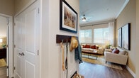 This single-story residence offers a thoughtfully designed layout with a cohesive modern aesthetic carried throughout each room. Wood-look flooring flows continuously across the living spaces, grounding the warm, neutral color palette accented by earthy tones.

The entryway provides a practical transition space with a wall-mounted coat and accessory rack. It opens directly into the living area, which features crown molding, a ceiling fan, and large windows fitted with blinds and sheer curtains that allow generous natural light. Bold accent walls and curated artwork add visual depth to the space.

The kitchen is well-equipped with granite countertops, a central island, gray cabinetry, stainless steel appliances, and a subway tile backsplash. The layout promotes efficient use of the cooking and prep space.

Multiple bedrooms offer a calm, restful atmosphere, each featuring ceiling fans, natural light from windows with blinds, and ample closet space—including at least one walk-in closet. The neutral taupe walls contribute to the serene character of the sleeping quarters.

The bathrooms are finished with granite-topped gray vanities, wood-look flooring, and a glass-enclosed shower in the primary bath, delivering a clean and polished look throughout.