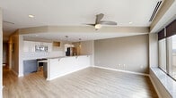 Located at 217 Second St NW in downtown Canton, Ohio, this thoughtfully designed one-bedroom unit offers a well-appointed layout across a single floor. The open-concept living and kitchen area serves as the heart of the space, featuring light luxury vinyl plank flooring, neutral warm-toned walls, and a ceiling fan with integrated lighting. A large bank of windows frames striking panoramic views of the Canton skyline, flooding the living area with abundant natural light.

The kitchen is a standout, outfitted with granite countertops, dark espresso lower cabinetry contrasted by crisp white upper cabinets, a white subway tile backsplash, and a full suite of stainless steel appliances. Pendant lighting over the breakfast bar adds a modern touch, and the generous counter space makes the kitchen as functional as it is stylish.

A clean, well-lit hallway connects the main living area to the private bedroom, which is carpeted for comfort and includes a ceiling fan. The bedroom features a walk-in closet with built-in dark wood shelving and cabinetry, providing excellent storage. The overall design aesthetic is clean and contemporary, combining modern finishes with a neutral palette to create a polished, move-in-ready living environment.