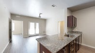 Located at 9000 Balch St in Fort Worth, TX, this single-story 2-bedroom, 2-bathroom home offers a well-designed open-concept layout. The combined kitchen and dining area serves as the heart of the home, featuring rich dark-wood cabinetry, granite countertops, a breakfast bar peninsula with an undermount sink, and stainless steel and black appliances. Wood-look plank flooring extends throughout the main living areas, adding warmth and continuity. The living room is bright and airy, with a ceiling fan, neutral wall tones, and French doors that open to a private patio, filling the space with natural light. Both bedrooms are comfortably sized with wood-look flooring, ceiling fans or light fixtures, and windows with blinds. The generously proportioned primary bedroom offers ample space. Four closets throughout the home provide excellent storage. The two bathrooms are finished with granite-top dark wood vanities and tile flooring; one includes a tub-shower combo with brushed nickel fixtures. A dedicated laundry room and a hallway connecting the key areas round out the efficient and functional floor plan, making this home practical for everyday living.