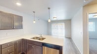 This single-floor residence at 6300 S Tallgrass Ave in Sioux Falls, South Dakota offers a clean, contemporary layout designed for comfortable everyday living. The kitchen is a standout feature, equipped with rich dark-stained cabinetry, light countertops, stainless steel appliances including a range, over-the-range microwave, refrigerator, and dishwasher. A peninsula with a double-basin sink and pendant lighting connects the kitchen to the open living and dining area, which is finished with wood-look flooring and sliding glass door access to the outdoors, allowing natural light to fill the space. The bedrooms are finished with plush carpeting and feature windows that bring in additional natural light, creating a calm and comfortable atmosphere. The primary bedroom includes a private en-suite bathroom with a walk-in shower, a vanity with a blue cabinet, and wood-look flooring. A second full bathroom features a single-sink vanity with dark cabinetry, a large mirror with overhead lighting, and matching wood-look flooring. The overall design is cohesive and modern, with neutral tones throughout, making it a well-appointed and move-in-ready home.