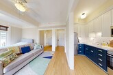 Located in the heart of Portland, OR, on SW Madison Street, this one-bedroom, one-bathroom residence offers a thoughtfully designed single-floor layout that makes efficient use of its intimate footprint. Light wood flooring flows throughout the unit, creating a warm and cohesive feel across every room.

The main living area connects seamlessly to both the bedroom and kitchen, offering an open, functional arrangement. A ceiling fan provides comfort overhead, while the living space benefits from natural light streaming in from large windows. The bedroom is generously proportioned relative to the overall unit size, featuring a tray ceiling detail and direct access to a private balcony framed by floor-to-ceiling French doors. These doors open to sweeping views of the Portland downtown skyline, filling the space with natural light and urban character. A classic radiator and an ornate gold-framed mirror add a touch of historic charm.

The kitchen stands out with a striking two-tone design: bold navy lower cabinetry contrasts with crisp white upper cabinets and subway tile backsplash. Stainless steel appliances, including a refrigerator, range, and over-the-range microwave, complete this efficient and stylish culinary space. A built-in open shelving unit adds additional storage.

The bathroom showcases classic tilework, with white subway wall tiles accented by teal border strips, penny-round mosaic floor tiles, and a frameless glass walk-in shower — a timeless aesthetic that reflects the building's heritage character.
