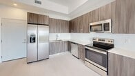 Located at 18300 SW 98th Ave in Palmetto Bay, FL, this modern single-floor unit offers a clean, contemporary design throughout. The open-concept living and kitchen area is anchored by a well-appointed kitchen featuring wood-grain cabinetry extending to the ceiling, white quartz countertops, a subway tile backsplash, and a full suite of stainless steel appliances including a French door refrigerator with ice maker, electric range, built-in microwave, and dishwasher. Light-toned flooring flows throughout, enhancing the bright, airy atmosphere.

The living area connects seamlessly to a private balcony through floor-to-ceiling sliding glass doors, offering expansive views of the lush Palmetto Bay skyline and surrounding greenery. The bedrooms are generously sized, bathed in natural light, and include closet storage. One room also features direct balcony access, further integrating indoor and outdoor living.

The bathroom is finished in a modern style with a wood-toned vanity, white countertop, frameless glass walk-in shower, and recessed lighting. The overall design emphasizes clean lines, neutral tones, and functional elegance, making this a well-crafted residence in a vibrant South Miami-Dade community.