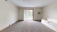 Located at 1405 Marion Rd SE in Rochester, Minnesota, this single-floor residential unit offers a well-organized and functional layout across several distinct living areas. The galley-style kitchen is equipped with warm oak cabinetry, granite-look countertops, wood-look flooring, and a full suite of white appliances including a range, refrigerator, dishwasher, and microwave — providing ample storage and prep space in a compact, efficient design. Adjacent to the kitchen is a dedicated dining area with carpet flooring, offering a comfortable space for everyday meals. The spacious living room features plush carpeting, a wall-mounted air conditioning unit, baseboard heating, and a sliding glass door that opens to a private balcony with outdoor views, allowing natural light to fill the room. The two bedrooms are carpeted and each include windows that bring in natural light; the primary bedroom features a built-in closet with shelving, while a second bedroom offers a double sliding-door closet for generous storage. The full bathroom includes a single-sink vanity with oak cabinetry, a wide mirror, wood-look flooring, and a shower/tub combo. Neutral tones and warm wood trim accents are consistent throughout, giving the unit a cohesive and inviting feel.