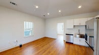 Located at 1821 W Mitchell St in Fayetteville, Arkansas, this one-bedroom, one-bathroom unit offers a well-designed single-floor layout that makes efficient use of its compact footprint. Warm-toned hardwood floors run throughout the entire space, lending a consistent and inviting character to every room.

The kitchen is a standout feature, outfitted with crisp white shaker-style cabinetry, light stone-look countertops, a stainless steel farmhouse sink, and a full suite of stainless steel appliances including a refrigerator with ice maker, electric range, over-the-range microwave, and dishwasher. Recessed lighting adds a polished touch overhead.

The combined kitchen and living area flows openly, providing a functional and comfortable everyday living space. The bedroom is well-proportioned, featuring multiple windows dressed with white blinds that admit generous natural light and offer views of the surrounding greenery. A ceiling fan provides added comfort. Clean white walls throughout the unit create a bright, neutral backdrop.

The bathroom is finished with a full tub-shower combination with chrome fixtures, set against clean white surroundings. The overall ambiance of the unit is clean, bright, and move-in ready, reflecting thoughtful updates throughout.