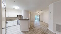 Located on Woodberry Trail Lane in Charlotte, NC, this well-appointed three-bedroom, two-bathroom residence offers a thoughtfully designed single-floor layout. The open-concept living area seamlessly connects the kitchen, dining, and living spaces, all finished with light wood-look flooring that enhances the bright, airy atmosphere. The kitchen is a standout feature, equipped with white shaker-style cabinetry, granite countertops, stainless steel appliances including a refrigerator, microwave, and range, and a peninsula that provides additional counter space and casual seating. Crown molding and wainscoting detailing add refined architectural character to the living and dining areas. A ceiling fan and sliding glass doors lead to a private balcony with tree-lined views, extending the living space outdoors. The bedrooms are carpeted for comfort, with the secondary bedrooms offering ample natural light and closet access. Both bathrooms feature granite-topped vanities, white cabinetry, and tiled tub-shower combinations with light wood-look flooring. Additional conveniences include a pantry, dedicated laundry area, and five closets throughout, ensuring generous storage. The overall palette of neutral tones creates a clean, inviting environment throughout the home.