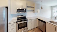 Located at 1315 Harding Pl in Charlotte's vibrant 28204 neighborhood, this single-floor residence offers a thoughtfully designed layout with contemporary finishes throughout. The kitchen is a standout feature, appointed with a full suite of stainless steel appliances including a range, microwave, dishwasher, and side-by-side refrigerator with ice maker. White shaker-style cabinetry, light granite countertops, and a classic subway tile backsplash complete the look, while warm wood-tone flooring and a stylish pendant light add warmth and character. Ample upper and lower cabinet storage, along with open shelving, provide excellent functionality. The bedrooms are finished with plush carpeting and feature large windows that frame views of the surrounding urban landscape, filling each room with natural light. A ceiling fan in the primary bedroom adds comfort and airflow. The primary bathroom is elegantly appointed with a dual-sink vanity featuring dark granite countertops, light wood-tone flooring, and access to both a glass-enclosed shower and a walk-in closet with built-in shelving. The overall aesthetic is clean, modern, and move-in ready, making this Charlotte residence a well-appointed and functional urban home.