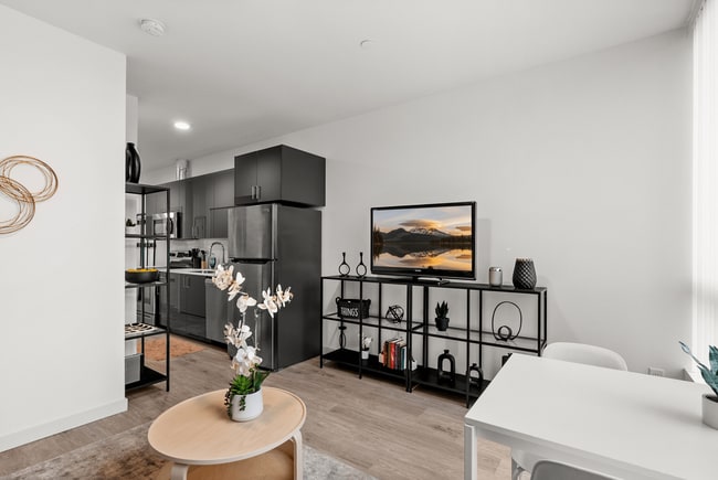 Open-concept living area with modern kitchen and stylish finishes. - The Ruby Apartments