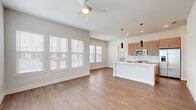 Located at 604 Visteria Blvd in North Venice, FL, this well-appointed single-story home offers 2 bedrooms and 2 bathrooms within a thoughtfully designed floor plan. The open-concept living, dining, and kitchen area serves as the heart of the home, featuring warm wood-look flooring, a ceiling fan, and an abundance of natural light streaming through large windows with white blinds. The kitchen is a standout, showcasing a spacious white waterfall island with an integrated sink, warm wood cabinetry, a white subway tile backsplash, stainless steel appliances, and sleek pendant lighting overhead. A pantry provides additional storage convenience. Both bedrooms are carpeted and well-lit with multiple windows framing outdoor views, creating a comfortable and airy feel. The primary bedroom is generously sized and includes closet space. The bathrooms are finished with quartz-topped vanities, modern fixtures, and illuminated mirrors. A den adds flexible living space, while a dedicated laundry area and multiple closets enhance functionality. The home also includes a patio for outdoor enjoyment. Clean white walls, consistent flooring, and modern hardware throughout lend the space a cohesive, contemporary aesthetic ideal for Florida living.