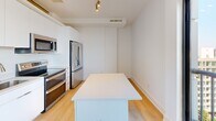 Located at 1150 4th St SW in Washington, DC, this two-bedroom, two-bathroom unit offers a thoughtfully designed single-level layout with a clean, modern aesthetic. Light wood-tone flooring runs throughout, complementing the crisp white walls and creating a bright, cohesive feel across all rooms.

The kitchen serves as a functional centerpiece, featuring stainless steel appliances—including a French door refrigerator and range—alongside white cabinetry and a central island with a white countertop. Track lighting overhead adds a contemporary touch. The open layout connects efficiently to the rest of the unit via a hallway.

Both bedrooms are well-proportioned, finished with the same light flooring and ceiling fans for added comfort. A notable architectural detail is the clerestory-style window strip positioned high on the wall in each bedroom, allowing natural light to filter in while maintaining privacy. The primary bedroom includes access to a dedicated closet.

The two bathrooms maintain the unit's clean palette. One features subway tile surrounding a soaking tub and shower combination with chrome fixtures, while the other offers a glass-enclosed shower, a white floating vanity, and large-format tile flooring. Both bathrooms are finished in bright whites, reinforcing the unit's contemporary, minimalist character throughout.