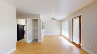 This single-floor, one-bedroom, one-bathroom residence offers a practical and comfortable layout designed to maximize every square foot. The living room serves as the heart of the home, featuring warm-toned hardwood flooring, a ceiling fan with light fixture, and a sliding glass door dressed with vertical blinds that floods the space with natural light. A charming pass-through window connects the living area to the kitchen, adding an open, communicative feel between the two spaces. The kitchen is equipped with a refrigerator and cabinetry, with tile flooring that transitions seamlessly from the main living areas. Multiple louvered-door closets throughout provide generous storage options, a notable feature for a space of this size. The bedroom is carpeted for comfort, outfitted with its own ceiling fan, a wide horizontal window, and two closets offering ample storage. The bathroom features a tiled tub-shower combo with a decorative diamond-tile accent border, lending a classic touch to the clean, white finish. Textured ceilings are present throughout the residence, and neutral wall tones create a bright, cohesive ambiance from room to room.
