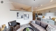Located at 313 Liggett St in Durham, NC, this thoughtfully designed studio offers a modern, efficient layout across a single floor. The open-concept kitchen and living area serves as the heart of the space, where light wood-tone flooring flows throughout, creating a warm and cohesive atmosphere. The kitchen is outfitted with gray shaker-style cabinetry accented by matte black hardware, a striking geometric white tile backsplash, light quartz countertops, stainless steel appliances including a range and built-in microwave, and a deep undermount sink with a matte black faucet. Natural light pours in through large windows overlooking the surrounding neighborhood, enhancing the open feel of the living area. The living space features impressively high ceilings with a ceiling fan, adding volume and airiness to the compact footprint. A barn-style door adds a contemporary architectural detail, while two closets provide practical storage solutions. The full bathroom is finished with elongated gray subway tile surrounding the tub and shower, light tile flooring, and matte black fixtures, maintaining the sleek, modern aesthetic found throughout the rest of the studio. Recessed lighting and clean white walls complete the polished, urban-contemporary character of this Durham residence.
