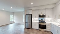 This well-designed one-bedroom, one-bathroom residence offers a thoughtfully planned single-level layout with modern finishes throughout. The open-concept living and kitchen area creates a seamless flow, anchored by warm wood-tone luxury vinyl plank flooring that extends through the main living spaces.

The kitchen is a standout feature, equipped with a full suite of stainless steel appliances including a gas range, over-the-range microwave, French door refrigerator, and dishwasher. Crisp white flat-front cabinetry reaches to the ceiling, maximizing storage, while a striking textured mosaic tile backsplash in neutral tones adds visual interest. White quartz countertops complete the clean, contemporary aesthetic.

The bedroom is bright and airy, benefiting from multiple windows that invite natural light and offer views of surrounding greenery. The neutral wall palette and wood-tone flooring create a calm, versatile space.

The bathroom is finished with marble-look tile surrounding the soaking tub and shower combination, complemented by a decorative mosaic tile floor. Built-in open shelving provides convenient storage, while the overall design maintains a clean, spa-like feel.

A closet with a hanging rod is accessible from the main living area, and recessed lighting throughout enhances the modern, polished character of this well-appointed residence.