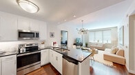 Located at 2 Center St in Newark, NJ, this well-appointed 2-bedroom, 2-bathroom residence offers a thoughtfully designed single-floor layout with modern finishes throughout. The open-concept kitchen and living area serves as the heart of the home, showcasing rich hardwood flooring, crisp white shaker cabinetry, dark granite countertops, and a full suite of stainless steel appliances including a refrigerator, range, microwave, and dishwasher. A peninsula with bar seating provides additional dining space and seamlessly connects the kitchen to the living room, which is bathed in natural light from large windows and offers access to a private balcony. A contemporary sputnik chandelier adds a stylish focal point to the dining area. The spacious primary bedroom features plush carpeting and direct access to the hallway, while the second bedroom offers a built-in closet and comfortable proportions. The primary bathroom is finished with large-format tile, a glass-enclosed walk-in shower, and a granite vanity, while the second bathroom includes a soaking tub and matching granite countertop. Clean white walls and recessed lighting throughout create a bright, cohesive ambiance across the entire residence.