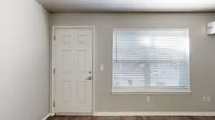 This efficiently designed one-bedroom, one-bathroom unit is laid out on a single floor, making the most of its compact footprint. The living room serves as the central gathering space, featuring rich wood-look flooring, neutral gray walls, and a textured ceiling with a ceiling fan and integrated light fixture. A large window fitted with horizontal blinds allows natural light to fill the room, while a wall-mounted mini-split unit provides climate control. The front entry door opens directly into this space, which connects seamlessly to the rest of the unit. The kitchen is galley-style and well-appointed, offering white cabinetry, granite-look countertops, a tile backsplash, a coil-burner electric range with overhead exhaust hood, and a full-size refrigerator — all finished with dark hardwood-style flooring that flows throughout the unit. The bedroom is a quiet, private retreat with access to a dedicated closet. The full bathroom includes a tiled tub-shower combination, a toilet, and a vanity with matching granite-look countertops. A separate closet adds practical storage. Neutral tones and consistent flooring throughout the unit create a cohesive, clean aesthetic.