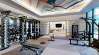 Located at 2500 Vantage Dr in Woodbridge, Virginia, this fitness center offers a comprehensive and thoughtfully organized workout environment across a single, generously sized floor. The space is divided into distinct functional zones, each purpose-built to support a full range of exercise disciplines.

The strength training area is a standout, anchored by a multi-station power rack with an extensive free weight selection, cable machines, and adjustable benches. Full-length mirrors line the walls, enhancing the sense of openness while allowing for proper form checks. Built-in shelving with a warm wood finish adds a refined, organized aesthetic to the space.

The cardio zone features a row of treadmills and cycling bikes, each equipped with individual screens for entertainment. Large floor-to-ceiling windows flood this area with natural light and offer views of the surrounding exterior, creating an energizing atmosphere. Additional cardio equipment, including ellipticals and a rowing machine, occupies an adjacent section.

A dedicated functional training area includes medicine balls, kettlebells, battle ropes, plyo boxes, and a heavy bag, supported by wood-plank flooring for versatile movement. The striking geometric ceiling detail — featuring teal, copper, and neutral panels with integrated fans and ambient lighting — ties the entire space together with a modern, polished design sensibility.