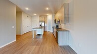 Located at 13650 Marsh View Blvd in Rogers, MN, this well-designed one-bedroom, one-bathroom unit offers a thoughtful single-floor layout with a comfortable and functional flow throughout. The open-concept kitchen and living area serves as the heart of the space, featuring light wood-toned cabinetry, a classic white subway tile backsplash, granite countertops, stainless steel appliances, and a freestanding island with built-in shelving — ideal for both meal prep and casual dining. Durable wood-look flooring runs throughout the main living areas, while recessed lighting adds a clean, modern touch. The living area extends toward sliding glass doors that open to a private balcony, inviting natural light and outdoor views. A separate den provides additional flexible space, complemented by a dedicated pantry and utility room for added convenience. Two closets offer ample storage throughout the unit. The bedroom is generously sized, finished with plush carpeting, a ceiling fan, and a window with neighborhood views. The full bathroom features a combination tub and shower, wood-look tile flooring, and a granite-topped vanity with modern cabinetry. Clean neutral tones and contemporary finishes create a cohesive, move-in-ready atmosphere throughout.