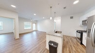 This single-floor, 2-bedroom, 2-bathroom residence features a thoughtfully designed open-concept layout that seamlessly connects the kitchen and living room. The kitchen serves as the centerpiece, showcasing a large granite-topped island with a built-in sink, white shaker cabinetry, a subway tile backsplash, stainless steel appliances, and stylish pendant lighting overhead. Warm wood-look plank flooring flows throughout the entire unit, providing visual continuity and a clean, modern aesthetic.

The living area is bright and spacious, benefiting from natural light through sliding glass doors that open to a private balcony, complemented by a ceiling fan overhead. Both bedrooms are well-proportioned and finished with the same wood-look flooring, ceiling fans, and window treatments offering outdoor views. The primary bedroom includes a dedicated walk-in closet with built-in wire shelving, while a second closet provides additional storage.

The two bathrooms are finished with light tile flooring, granite-topped vanities with white cabinetry, and tub-shower combinations featuring white tile surrounds. Throughout the residence, the crisp white walls, recessed lighting, and consistent finishes create a clean, contemporary ambiance that is both functional and inviting.