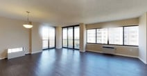 This single-floor residence offers a thoughtfully designed layout with a spacious, open-plan living and dining area at its core. Dark hardwood-style flooring runs throughout, providing a warm contrast to the neutral, cream-toned walls and textured ceilings. Large floor-to-ceiling windows and sliding glass doors lead to a private balcony, flooding the living space with natural light and offering expansive city views of the surrounding skyline.

The galley-style kitchen features dark espresso cabinetry, white countertops, and stainless steel appliances, with a pass-through window connecting it to the main living area. A pendant light above the pass-through adds a functional design detail.

The bedrooms are well-sized, each featuring dark hardwood-style floors, neutral walls, and built-in closets with wire shelving. One bedroom includes a walk-in closet with full shelving and hanging space, offering ample storage.

Two bathrooms serve the residence. One features a walk-in shower with a glass sliding door, dark wood vanity cabinetry, and white countertops. The second includes a soaking tub with white tile surround, a curved shower rod, and grab bar safety features. Both bathrooms are finished with clean, functional fixtures throughout.