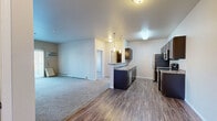 Located at 5450 26th St S in Fargo, North Dakota, this 2-bedroom, 2-bathroom unit offers a functional and comfortable single-floor layout. The kitchen features rich dark cabinetry, granite-style countertops, wood-look vinyl flooring, and stainless steel appliances including a refrigerator, electric range, microwave, and dishwasher. The open layout connects seamlessly to the living area, which is carpeted and filled with natural light through a sliding glass patio door dressed with vertical blinds, providing outdoor views of the surrounding neighborhood. Wall-mounted heating and cooling units are present throughout. Both bedrooms are carpeted and well-sized, with the primary bedroom offering generous proportions and large windows that invite natural light. Each bathroom is finished with dark vanity cabinetry, granite-style countertops, and wood-look vinyl flooring; one includes a tub-shower combination. A dedicated in-unit laundry room with a full-size washer and dryer and overhead shelving adds everyday convenience. The unit also includes a closet for additional storage. Baseboard heating runs throughout the carpeted spaces, ensuring comfort year-round in the North Dakota climate.