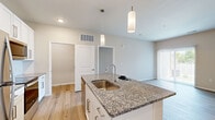 This single-story, two-bedroom, two-bathroom residence in Blue Springs, Missouri offers a thoughtfully designed open-concept layout finished with contemporary details throughout. The kitchen and living area flow seamlessly together, anchored by a central island topped with granite countertops and equipped with a undermount sink illuminated by stylish pendant lighting. White shaker cabinetry, a subway tile backsplash, and stainless steel appliances — including a refrigerator, range, and microwave — complete the kitchen. Light hardwood-style flooring runs through the main living areas, creating a warm and cohesive aesthetic.

Both bedrooms feature soft carpeting and neutral tones; the primary bedroom offers a ceiling fan, natural light from a large window, and access to a spacious walk-in closet with multi-tier wire shelving. The primary bathroom includes granite countertops, white cabinetry, and a glass-enclosed shower. The second bathroom features a full tub-shower combination with tile surround. A dedicated laundry room houses a full-size Whirlpool washer and dryer with overhead wire shelving for added storage.