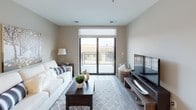 The High Pointe 2 Bed 2 Bath is a thoughtfully designed single-floor residence that balances modern aesthetics with functional living. The kitchen serves as a standout feature, showcasing rich dark cabinetry paired with granite countertops, stainless steel appliances including a refrigerator, range, microwave, and dishwasher, and durable wood-look flooring. A breakfast bar provides additional workspace and casual dining space, while recessed and pendant lighting enhance the room's polished atmosphere.

The living area features the same wood-look flooring and is anchored by large sliding glass doors that open to a private balcony, inviting natural light and outdoor views into the space. Both bedrooms are carpeted for comfort and equipped with ceiling fans. Large windows frame exterior views, and each bedroom offers generous storage with walk-in or standard closet configurations.

The two bathrooms are finished with granite-topped dark vanities and frameless sliding glass shower enclosures set against clean, light-toned tile surrounds, lending a sleek, contemporary feel. Chrome fixtures throughout add a cohesive, refined touch. The overall design palette of neutral tones, quality finishes, and modern fixtures creates a comfortable and sophisticated living environment.
