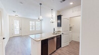Located at 12701 Eastlake Blvd in El Paso, TX, this well-appointed one-bedroom, one-bathroom residence offers a thoughtfully designed single-floor layout. The open-concept living and kitchen area serves as the heart of the home, where light-toned luxury vinyl plank flooring flows throughout, complemented by crisp white walls that maximize brightness. The kitchen is a standout feature, showcasing a large granite-topped island with a built-in sink, dark espresso cabinetry reaching to the ceiling, stainless steel appliances including a refrigerator, electric range, microwave, and dishwasher, and stylish pendant lighting overhead. A ceiling fan anchors the adjacent living area, which receives natural light through double windows and offers direct access to an outdoor area via a glass door. The generously sized bedroom is carpeted for comfort and connects to a spacious walk-in closet outfitted with double hanging rods and shelving. The full bathroom features a tiled tub-shower combination, dark bronze fixtures, a granite-topped vanity, and wood-look flooring. A dedicated laundry room with a full-size washer and dryer completes this practical and polished home.