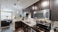 Located in Charlotte's 28211 zip code, this one-bedroom, one-bathroom residence offers a thoughtfully designed single-floor layout that maximizes every square foot. The kitchen is a standout feature, showcasing rich dark espresso cabinetry, granite-style countertops, a classic white subway tile backsplash, and a full suite of stainless steel appliances including a range, microwave, and refrigerator. Pendant lighting and track lighting add a polished finishing touch. The open layout allows the kitchen to flow naturally into the living area, which features warm hardwood-style flooring, neutral toned walls, and a ceiling fan overhead. Natural light enters through blinds-fitted windows, creating a bright and inviting atmosphere. The generously sized bedroom accommodates large furnishings comfortably, complete with its own ceiling fan and large window. It connects directly to a full bathroom featuring dark cabinetry with granite countertops, matching the kitchen's aesthetic, and a tub-shower combination. A dedicated walk-in closet equipped with multi-level wire shelving provides ample storage. Hardwood-style flooring runs throughout the main living spaces, tying the home's modern, cohesive design together.