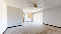 This single-floor studio unit offers an efficient and well-organized layout designed to maximize functionality within a cozy footprint. The open living area features wall-to-wall carpet, dark baseboards, and a textured ceiling fitted with a ceiling fan and light fixture, providing both comfort and airflow. A large sliding glass door dressed with vertical blinds fills the space with natural light and offers access to the outdoors.

The galley-style kitchen is thoughtfully appointed with white shaker cabinetry accented by sleek bar-pull hardware, light stone-look countertops, and light wood-tone flooring. Stainless steel appliances—including a refrigerator, dishwasher, and range—lend a modern, clean aesthetic. A pass-through counter connects the kitchen to the living area, enhancing the open feel. A louvered bifold door provides access to additional storage within the kitchen corridor.

The bathroom is clean and bright, featuring a full tub-shower combination with white tile surround, wood-look vinyl flooring, and white cabinetry with stone-look countertops. The unit also includes a separate entry area and an additional carpeted room ideal for use as a bedroom, complete with its own ceiling fan. Neutral tones throughout create a cohesive, move-in-ready ambiance.