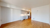 Located at Minor Ave N in Seattle's vibrant South Lake Union neighborhood, this single-floor unit offers a clean, modern design with an efficient and well-appointed layout. The open-plan living area is anchored by warm-toned hardwood flooring that extends throughout the space, complementing the bright white walls and recessed lighting overhead. Large sliding glass doors lead to a private balcony, flooding the interior with natural light and offering views of the surrounding urban streetscape.

The integrated kitchen is thoughtfully designed with sleek gray cabinetry, white countertops, and a full suite of stainless steel appliances including a refrigerator, oven, and dishwasher — providing a functional yet stylish cooking space that flows seamlessly into the living area.

The bathroom maintains the same modern aesthetic, featuring a white vanity with an undermount sink, a large mirror, tiled shower walls, and the same hardwood-style flooring found throughout the unit, creating a cohesive and polished look.

Overall, the space presents a minimalist, contemporary ambiance with a neutral palette, making it a versatile and inviting environment well-suited to urban living in one of Seattle's most dynamic neighborhoods.