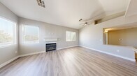 Located at 2750 W Wigwam Ave in Las Vegas, NV, this one-bedroom, one-bathroom unit offers a well-designed single-floor layout with thoughtful architectural details throughout. The open living room is a standout space, featuring vaulted ceilings, a ceiling fan, a classic white-mantled fireplace, and multiple windows dressed with horizontal blinds that allow ample natural light to fill the room. Light wood-style luxury vinyl flooring runs throughout the entire unit, lending a clean and cohesive aesthetic. The kitchen is efficiently designed with white shaker-style cabinetry, light stone countertops, stainless steel appliances including a refrigerator, gas range, and microwave, and a window above that brings in additional natural light. The bedroom offers a comfortable layout with a bay window configuration, providing a bright and airy feel. A dedicated closet adds practical storage. The bathroom includes a full-size soaking tub and shower combination with clean white tile surround and chrome fixtures. Neutral gray-toned walls and crisp white trim complete the interior palette, creating a modern and move-in-ready atmosphere throughout the unit.