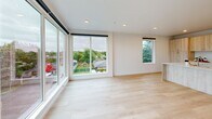 This thoughtfully designed two-bedroom, two-bathroom apartment in Vancouver, WA offers a clean, contemporary aesthetic throughout its well-appointed single-floor layout. The open-concept living and kitchen area serves as the heart of the unit, bathed in natural light from expansive floor-to-ceiling windows and a sliding glass door that frame views of the surrounding neighborhood. Light hardwood flooring runs throughout the main living areas, complementing the bright, neutral color palette and recessed lighting overhead. A wall-mounted mini-split system provides efficient climate control in the living space.

The kitchen is a standout feature, showcasing light wood cabinetry, a large quartz-topped island with an undermount sink, stainless steel appliances, and a matching quartz backsplash — all combining for a sleek, modern feel. Both bathrooms mirror this design language, featuring wood-toned vanities with quartz countertops and large mirrors.

The two bedrooms offer comfortable proportions with plush wall-to-wall carpeting, crisp white walls, and ample natural light. The primary bedroom includes a sliding-door closet, while both bedrooms provide a calm, restful atmosphere. A connecting hallway ties the layout together efficiently, making this apartment a well-balanced and stylish living space.