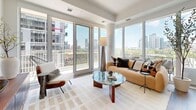 Located in the heart of Toronto's King West neighbourhood, this well-appointed two-bedroom, two-bathroom residence offers a thoughtfully designed layout with modern finishes throughout. Light hardwood flooring flows across the entire unit, complementing the clean, contemporary aesthetic.

The open-concept living and kitchen area is anchored by expansive floor-to-ceiling windows that bathe the space in natural light and frame sweeping views of the Toronto skyline. Sliding glass doors lead directly to a private balcony, seamlessly blending indoor and outdoor living. The kitchen features flat-panel light wood cabinetry, stainless steel appliances, and a textured tile backsplash that adds visual interest.

The primary bedroom is a serene retreat with direct balcony access through large sliding glass doors, offering additional city views and natural light. The second bedroom features warm textured wallcovering, a double closet, and its own connection to the balcony.

Both bathrooms are finished with elevated design details. The main bath includes a glass-enclosed walk-in shower with subway tile walls and a marble mosaic floor, while the second bath features a striking terracotta-toned geometric accent wall paired with a floating light wood vanity and built-in shelving. This residence combines urban convenience with refined, comfortable living.
