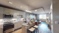 This single-floor residence showcases a thoughtfully designed open-concept layout that seamlessly connects the kitchen, dining, and living areas. The kitchen is a standout feature, outfitted with light wood cabinetry, granite countertops, a decorative mosaic tile backsplash, stainless steel appliances, and a central island with bar seating — ideal for both casual dining and entertaining. A linear pendant light adds a modern finishing touch overhead.

The living area flows naturally from the kitchen and is defined by a tray ceiling, rich hardwood-style flooring, and a muted gray accent wall that adds depth and sophistication. Large windows allow natural light to fill the space and offer views of the surrounding area, while sheer curtains provide a soft, airy ambiance.

The bedrooms are well-proportioned and carpeted for comfort, each benefiting from ample natural light through generously sized windows. Ceiling fans and neutral tones create a calm, restful atmosphere.

The bathroom features granite countertops consistent with the kitchen's design language, with direct access to a walk-in closet, enhancing the home's functional layout.

Throughout, the residence maintains a cohesive modern aesthetic with warm tones, quality materials, and carefully considered details that balance style with everyday livability.
