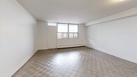 Located on the 9th floor at 2460 Weston Road in Toronto, this 2-bedroom, 1-bathroom unit offers a well-organized layout across a single floor. The combined kitchen and living area forms the heart of the home, where a modern kitchen stands out with white cabinetry, subway tile backsplash, stainless steel appliances including a French door refrigerator, dishwasher, and electric range, and a central island with a dark countertop that doubles as a breakfast bar. The living room receives generous natural light through large windows, offering elevated city views, and features a distinctive checkerboard-patterned parquet floor. Both bedrooms are comfortably proportioned, with the primary bedroom featuring mirrored sliding closet doors and parquet flooring, alongside windows that bring in natural light. The second bedroom is equally bright, with its own window and baseboard heating. The full bathroom is clean and contemporary, finished with white subway tile surrounding a soaker tub and shower, a vanity with under-sink storage, and neutral tile flooring. A hallway connects the main entry to all rooms, providing a functional flow throughout the unit.