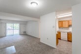 This single-floor unit offers a practical and functional layout designed for comfortable everyday living. The living area is generously proportioned, featuring neutral-toned carpet and a sliding glass door fitted with vertical blinds that floods the space with natural light and provides views of the surrounding greenery. A structural beam detail adds subtle architectural definition to the open living space.

The kitchen is separated from the living area by a partial wall, creating a semi-open layout. It is equipped with warm oak cabinetry offering ample storage, light-toned laminate countertops, a stainless steel sink, a dishwasher, and a coil-top range. Tile-style flooring runs throughout the kitchen, contrasting with the carpeted living and sleeping areas.

The bedrooms are carpeted and well-sized, each featuring standard closets with hanging rods for storage. Windows allow natural light into the sleeping areas, contributing to a bright and airy atmosphere. The bathroom includes a wood-toned vanity with a white countertop, an integrated sink, a mirrored medicine cabinet, and a towel bar, maintaining the unit's consistent, functional aesthetic throughout.