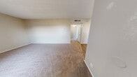 Located at 8401 Spain Rd NE in Albuquerque, New Mexico, this two-bedroom, one-bathroom single-floor unit offers a practical and comfortable layout. The living room is a welcoming, open space featuring plush carpeting, neutral beige walls, a textured ceiling, and a large front-facing window fitted with blinds that allows natural light to fill the room. A hard-surface entryway transitions seamlessly into the carpeted living area.

The kitchen is well-appointed with white shaker-style cabinetry, white countertops, and a full suite of stainless steel appliances including a refrigerator, electric range, over-the-range microwave, and dishwasher. Light wood-look flooring and a window above the sink add brightness and a clean, modern feel.

The primary bedroom is a comfortable size, featuring carpet flooring, a ceiling fan with light fixture, a window with blinds, and neutral-toned walls. The second bedroom is similarly finished with carpet and soft neutral tones. Both rooms offer a quiet, restful atmosphere.

The bathroom includes a full tub-shower combination with clean white surrounds, brushed nickel fixtures, and a towel bar. A hallway connects the main living areas to the bedrooms, closet, and bathroom, keeping the layout organized and efficient. Overall, the unit presents a clean, move-in ready aesthetic throughout.