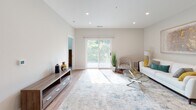 This well-designed single-floor residence combines modern aesthetics with functional living spaces, offering a bright and welcoming atmosphere throughout. The open-concept living area is bathed in natural light streaming through large sliding glass doors that lead to an outdoor balcony, framing lush green tree views. Light hardwood flooring, recessed lighting, and neutral wall tones create a clean, contemporary feel across the main living space.

The kitchen is a standout feature, showcasing crisp white shaker cabinetry, a subway tile backsplash, quartz countertops, and a full suite of stainless steel appliances including a refrigerator, range, and microwave. A generous island with seating for three provides both additional prep space and a casual dining option, with stylish pendant lighting overhead.

The bedroom is a calm retreat, featuring plush carpeting, a ceiling fan with integrated lighting, and a large window with blinds that fills the room with soft natural light. A doorway leads to a walk-in closet area, adding to the room's practicality.

The bathroom is finished to a high standard, featuring a dual-sink vanity with ample cabinetry, a frameless glass sliding shower enclosure over a soaking tub, and light wood-look flooring that ties the clean, neutral palette together seamlessly.