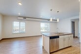 Located at 2065 South Cherokee Street in Denver, CO, this modern one-bedroom, one-bathroom unit offers a well-designed open-concept layout across a single floor. The combined living, dining, and kitchen area serves as the heart of the home, featuring light wood-style flooring, recessed lighting, and large windows that frame panoramic views of the Denver cityscape and surrounding landscape. The kitchen is thoughtfully outfitted with white cabinetry extending to the ceiling, a mosaic tile backsplash, stainless steel appliances including a refrigerator, range, microwave, and dishwasher, and a central island with a dark countertop and built-in sink, illuminated by pendant lighting overhead. The bedroom offers a comfortable, carpeted retreat with a ceiling fan, wall-mounted HVAC unit, and a window with outdoor views. It includes direct access to a dedicated walk-in closet with built-in wire shelving, providing generous storage. A second closet adds further organizational flexibility. The bathroom features wood-look flooring and a full tub-shower combo with classic white subway tile surround. An in-unit laundry area rounds out the functional amenities of this efficiently designed urban residence.