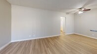 Located at 4640 Arden Way in El Monte, California, this one-bedroom, one-bathroom unit offers a practical and well-laid-out single-floor living space. The living room welcomes you with light wood-style laminate flooring, neutral gray walls, a textured ceiling, and a wall-mounted air conditioning unit positioned beside a large window with vertical blinds that allows natural light to fill the room. A hallway connects the main living areas to the private spaces within the unit. The kitchen features a galley-style layout with white cabinetry, granite-style countertops, a gas range, stainless steel refrigerator, over-the-range microwave, and a window at the end that brings in additional natural light. The kitchen flows openly into the combined living and dining area, which is also equipped with a ceiling fan. The bedroom offers comfortable carpeted flooring, soft neutral tones, a window with views of surrounding trees, and a sliding-door closet with built-in shelving for ample storage. The bathroom includes a full tub-shower combination finished in clean white subway tiles, with chrome fixtures and a window above for ventilation and light. A connecting hallway completes the efficient floor plan of this cozy El Monte residence.