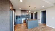 Located at 301 Debaliviere Ave in St. Louis, Missouri, this contemporary residential unit offers a thoughtfully designed single-level layout with modern finishes throughout. The open-concept kitchen is a standout feature, showcasing rich dark cabinetry, a textured blue-gray tile backsplash, stainless steel appliances including a refrigerator, range, microwave, and dishwasher, and a central island with pendant lighting overhead. Light hardwood flooring flows seamlessly throughout the entire unit, enhancing the sense of continuity and warmth. Floor-to-ceiling windows and glass sliding doors in the living area flood the space with natural light and provide direct access to a private balcony with open views of the surrounding St. Louis neighborhood. The bedrooms are generously sized, each benefiting from large windows, ceiling fans, and ample closet space. The bathrooms are finished with clean, modern details, including undermount sinks with marble-style countertops, dark matte black fixtures, wood-toned vanities, and frameless glass-enclosed walk-in showers with wood-look tile flooring. Neutral gray walls complement the contemporary aesthetic, creating a bright, move-in-ready living environment.