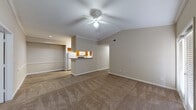 This single-story unit offers a well-organized layout designed for comfortable everyday living. The open-concept living area is immediately welcoming, featuring vaulted ceilings accented by crown molding and a ceiling fan with integrated lighting. Warm neutral tones on the walls complement the plush carpeted flooring throughout the living and bedroom areas, creating a cohesive and relaxed atmosphere.

The kitchen is accessed via a peninsula-style breakfast bar that opens to the living space, providing a functional and social cooking environment. Warm wood cabinetry pairs with granite-look countertops, and white appliances — including a refrigerator, electric range, and built-in microwave — are included. Wood-look vinyl flooring runs through the kitchen and extends into the connecting areas.

The bedrooms are generously proportioned, each equipped with ceiling fans and windows fitted with blinds for light control. The primary bedroom connects to a spacious walk-in closet with wire shelving along multiple walls, offering substantial storage. Two full bathrooms serve the unit, each featuring a tub-shower combination with tiled surround, wood-tone vanity cabinetry, white countertops, and wood-look flooring.
