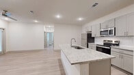 This single-story, 3-bedroom, 2-bathroom home offers a thoughtfully designed layout with modern finishes throughout. The open-concept kitchen serves as the heart of the home, anchored by a large granite-topped island with an integrated sink. Gray shaker-style cabinetry pairs elegantly with a full suite of stainless steel appliances, including a refrigerator, range, and microwave. Recessed lighting illuminates the space, which flows seamlessly into the living area, where light wood-style flooring extends throughout the home for a cohesive aesthetic.

The bedrooms are bright and well-proportioned, with the primary bedroom offering a comfortable footprint, ceiling fan, and access to a dedicated walk-in closet with built-in shelving and hanging rods. A total of four closets provide generous storage across the home. The bathrooms are finished with granite-topped vanities and gray cabinetry, with one bathroom featuring a shower-tub combo and built-in shelving for added convenience.

Light neutral tones on the walls complement the natural light that enters through windows dressed with horizontal blinds. The overall ambiance is clean, modern, and move-in ready, making efficient use of every square foot of the single-level floor plan.
