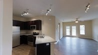 Located at 1211 Gray Birch Way in Knoxville, Tennessee, this two-floor home offers a thoughtfully designed layout with modern finishes throughout. The main level showcases an open-concept kitchen and living area that creates a seamless, inviting flow. The kitchen is outfitted with rich, dark cabinetry that provides a striking contrast against the light granite countertops. A kitchen peninsula with an integrated sink adds both functionality and a natural gathering point. Stainless steel appliances, including a gas range and built-in microwave, complete the well-appointed culinary space. Track lighting illuminates the kitchen area with precision, while a ceiling fan in the adjacent living room ensures year-round comfort. The living area benefits from an abundance of natural light, thanks to a set of elegant French doors that open to the outdoors, framing views of the surrounding greenery. Warm hardwood-style flooring runs throughout the main living spaces, adding continuity and a sense of warmth. Neutral wall tones provide a versatile backdrop that complements a variety of décor styles. The two-floor layout offers additional living space upstairs, making this home well-suited for a range of lifestyles.