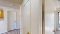 Located at 2851 Redwood Pkwy in Vallejo, CA, this one-bedroom, two-bathroom residence offers a thoughtfully arranged floor plan with a comfortable sense of space throughout. The living area is a standout, featuring soaring vaulted ceilings, a striking blue-tiled fireplace, wall sconce lighting, and plush carpeting, all framed by a staircase with a classic wood railing that adds architectural character. The kitchen is well-equipped with warm wood cabinetry, granite-style countertops, a gas range, and a full-size refrigerator, alongside a connected dining area for everyday convenience. The generously sized primary bedroom is a highlight of the home, offering mirrored sliding closet doors, plush carpeting, a large sliding glass door with vertical blinds that invite natural light, and access to outdoor views. Additional rooms feature wood-look flooring and large windows fitted with vertical blinds for light control and privacy. Both bathrooms are finished with wood-toned vanities, granite-style countertops, and bright overhead lighting. The textured ceilings appear throughout, lending a consistent finish to the home's neutral, light-toned interior palette.