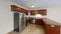 Located in Maple Grove, Minnesota, this two-floor home offers a practical and comfortable layout across both levels. The kitchen is a standout feature, appointed with rich warm-toned wood cabinetry, granite-style countertops, a full suite of stainless steel appliances including a refrigerator, range, microwave, and dishwasher, and a double sink. A peninsula provides additional counter space and opens toward the main living area, which features light wood-look flooring and large sliding glass doors that invite abundant natural light. Baseboard heating is present throughout the home. The bedrooms are carpeted and well-proportioned, with windows offering pleasant outdoor views of the surrounding greenery. One bedroom benefits from natural light streaming in through vertical-blind-covered windows overlooking a landscaped yard. The home includes two bathrooms: a full bath with a tub-shower combo, single vanity, and large mirror, and a half bath with a dark-framed mirror and wood vanity with chrome fixtures. A textured ceiling treatment is featured in select areas of the home. The overall interior presents a neutral, clean palette with warm wood accents, making it a functional and inviting space in a residential Maple Grove neighborhood.