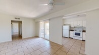 This single-floor, 2-bedroom, 1-bathroom unit offers a practical and efficient layout with light-toned ceramic tile flooring running consistently throughout all rooms. The open-concept living area is bright and airy, anchored by a ceiling fan with light fixture and a textured ceiling. A sliding glass door floods the space with natural light and provides access to an outdoor area, creating a seamless indoor-outdoor connection. The living area flows directly into the kitchen, which is equipped with white cabinetry, dark countertops, a white refrigerator, electric range, and a window that brings in additional natural light.

A hallway connects the living spaces to the private areas of the unit, leading to two bedrooms, a closet, and a full bathroom. The primary bedroom is generously sized and features direct access to both a closet and the bathroom. The second bedroom includes a window with blinds offering outdoor views. The bathroom is finished with tile flooring. The entryway includes a utility panel and a closet, adding practical storage near the front door. Overall, the unit maintains a clean, neutral palette throughout.