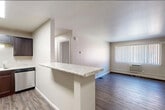 This well-appointed one-bedroom, one-bathroom unit offers a practical and efficient layout across a single floor. The open-concept kitchen and living area serves as the heart of the space, where a peninsula with a marble-style countertop separates the two zones while maintaining an open, connected feel. The kitchen is equipped with stainless steel appliances, including a full-size refrigerator and dishwasher, complemented by dark espresso cabinetry and a skylight that introduces additional natural light. A light marble countertop and under-cabinet lighting add functional detail to the workspace.

The living area extends from the kitchen and features dark hardwood-style flooring that runs consistently throughout the unit, lending a cohesive and modern aesthetic. A large window fitted with vertical blinds allows natural light to fill the room, while a wall-mounted air conditioning unit and baseboard heating provide year-round climate control.

The bedroom is a comfortable, well-proportioned room with a ceiling fan, a natural light window, and access to a closet with built-in shelving. The bathroom features a clean, white tub and shower surround with built-in shelving niches. Neutral wall tones and white trim throughout the unit contribute to a clean, move-in-ready appearance.